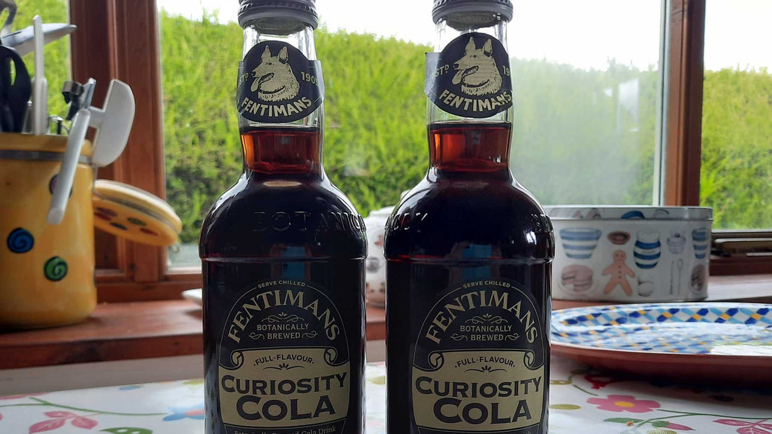 two bottle of Curiosity Cola on a table with window in the background