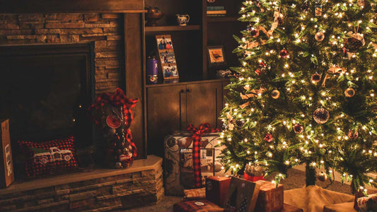 Christmas tree with presents underneath next to fireplace with decorations