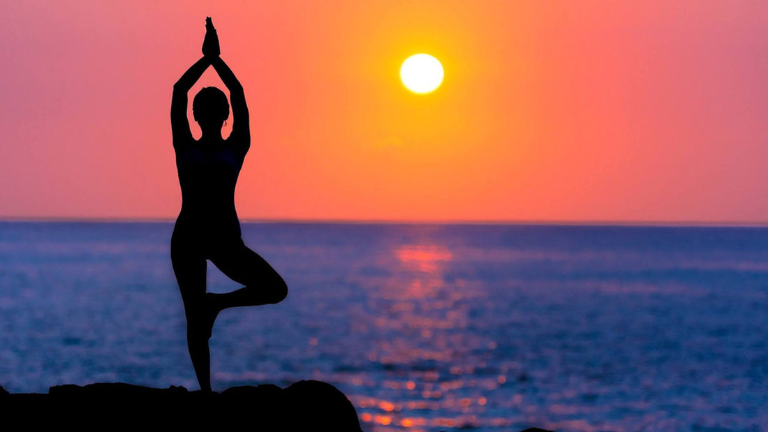 silhouette of woman in yoga pose in front of beautiful sunset to represent sober wellbeing