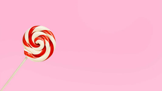red and white swirly candy cane against pink background to represent sugar