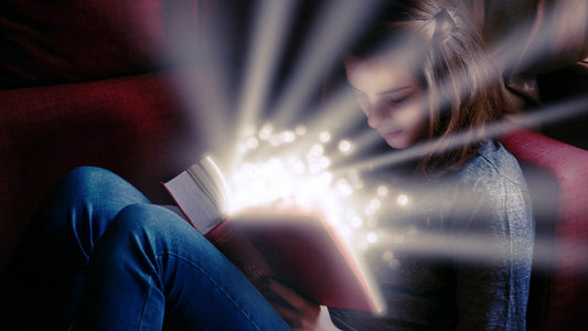 girl looking at book which is reflecting golden light into her face to represent how special she is