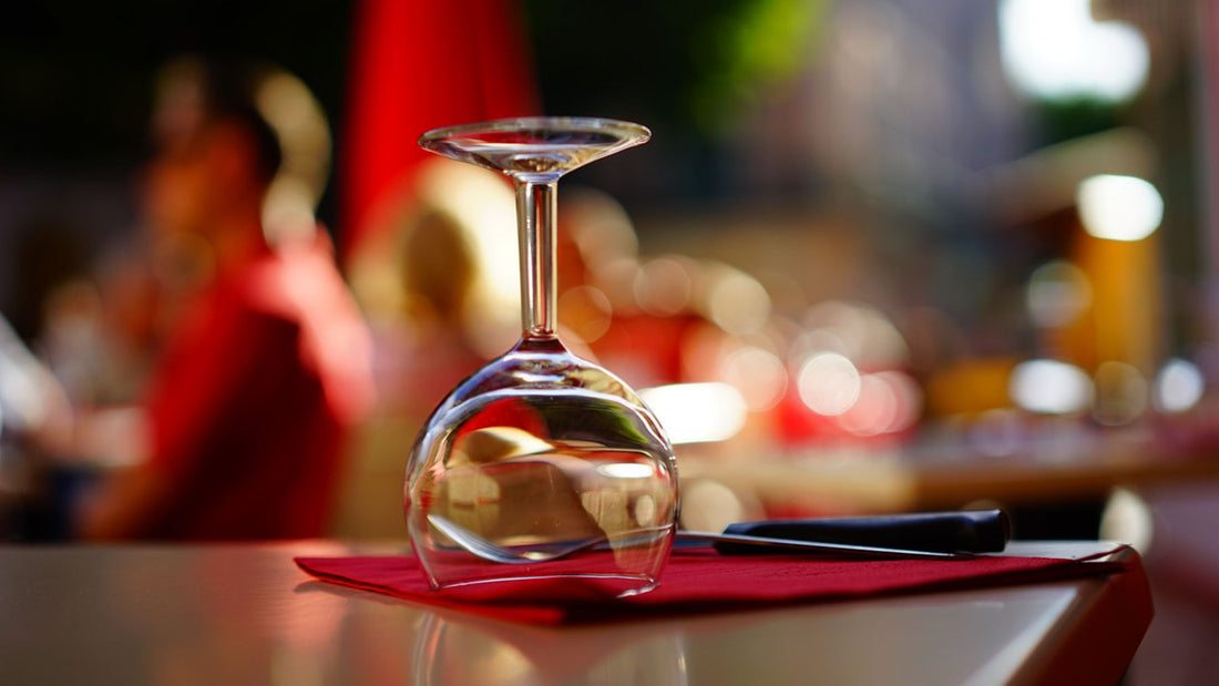 an upside down wine glass on a red napkin on a dressed table